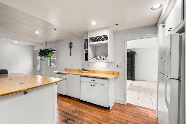 kitchen with white cabinets, wood counters, freestanding refrigerator, and light wood-style floors