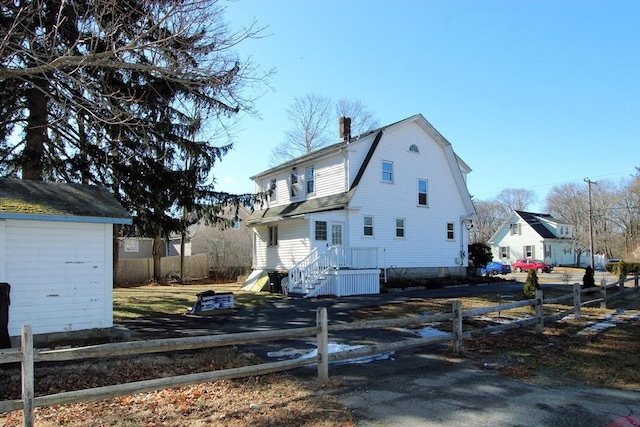 view of home's exterior featuring fence private yard, a chimney, and a gambrel roof