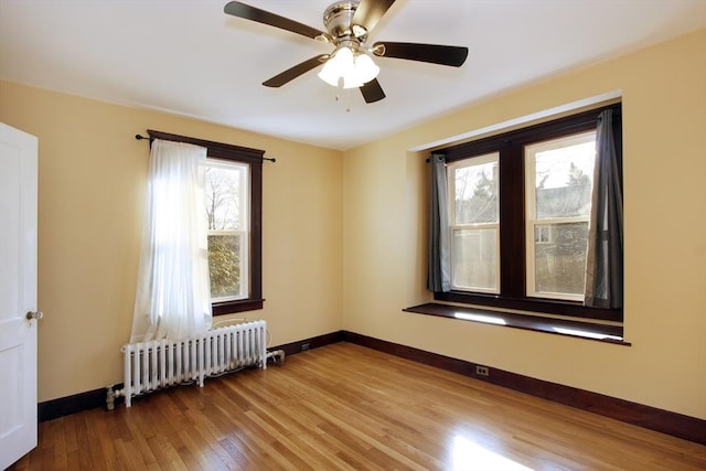 unfurnished room featuring radiator heating unit, wood finished floors, and baseboards