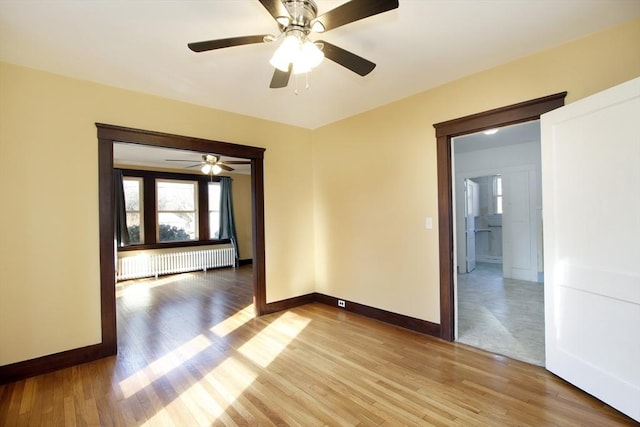 unfurnished room featuring light wood-type flooring, radiator, and baseboards