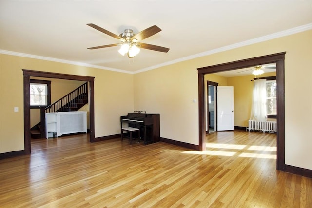 empty room with baseboards, stairway, light wood-type flooring, radiator, and crown molding