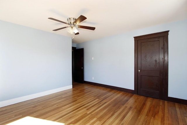 empty room featuring light wood-style flooring, baseboards, and a ceiling fan