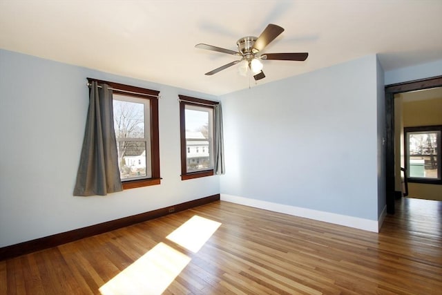 empty room with ceiling fan, baseboards, and wood finished floors