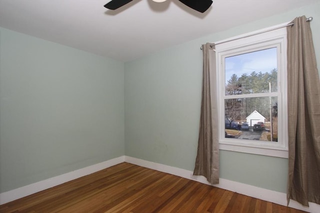 spare room with wood finished floors, a ceiling fan, and baseboards