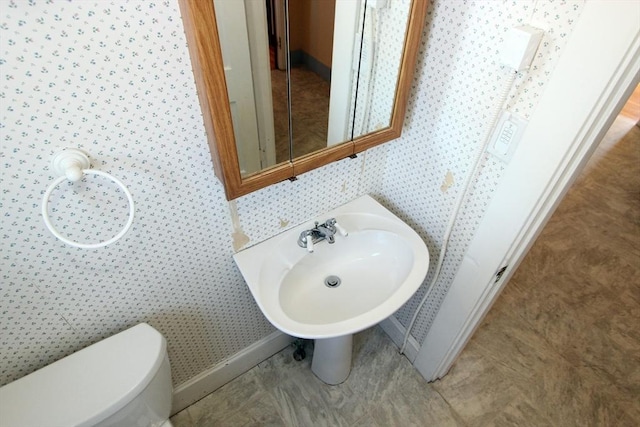 bathroom featuring baseboards, toilet, and wallpapered walls