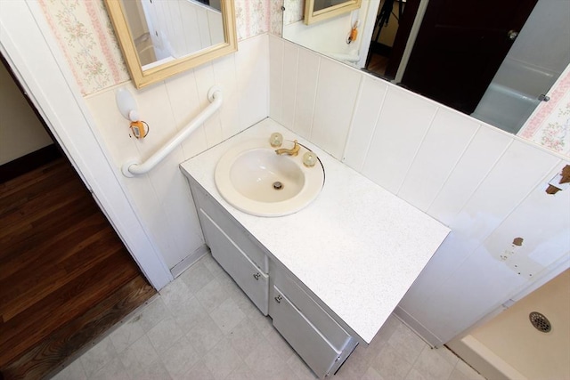 full bathroom featuring a wainscoted wall, vanity, and wallpapered walls