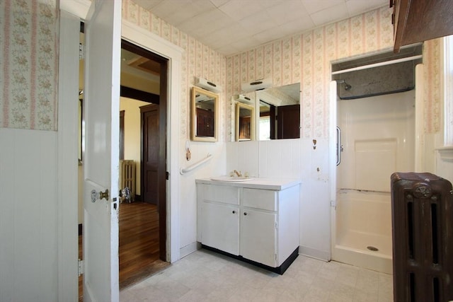 full bathroom featuring radiator heating unit, a shower stall, and wallpapered walls