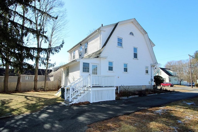 rear view of property featuring fence and a gambrel roof