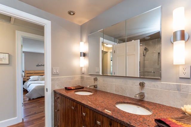 bathroom with tiled shower, vanity, backsplash, and wood-type flooring