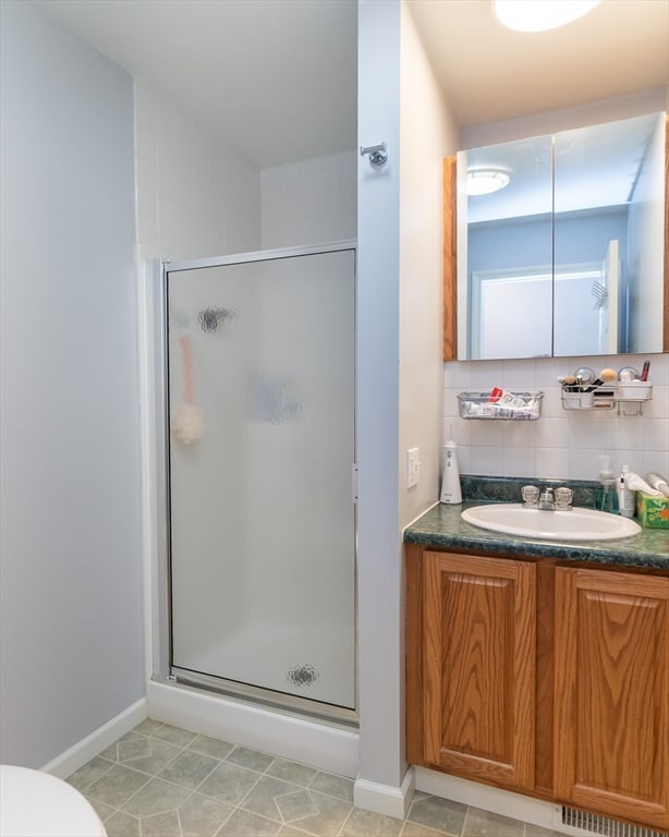 bathroom featuring a shower with shower door, toilet, vanity, and tasteful backsplash