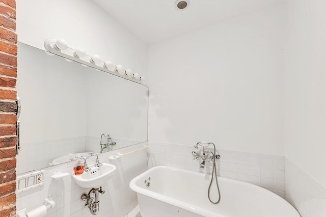 full bath featuring a freestanding tub, tile walls, and a wainscoted wall