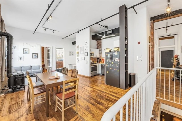 dining area featuring track lighting, wood-type flooring, and a wood stove