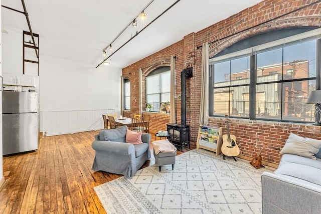 interior space featuring a wood stove, a wainscoted wall, brick wall, and hardwood / wood-style floors