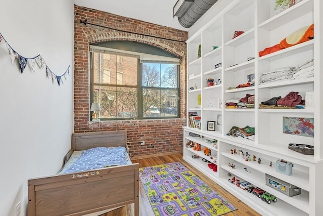 interior space with wood finished floors and brick wall