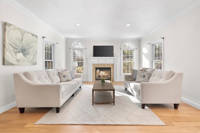 living room featuring a tiled fireplace, light wood-type flooring, and ornamental molding