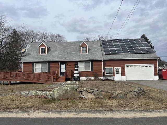 view of front facade featuring a garage, roof with shingles, solar panels, and driveway