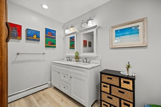 bathroom with baseboard heating, hardwood / wood-style floors, and dual bowl vanity