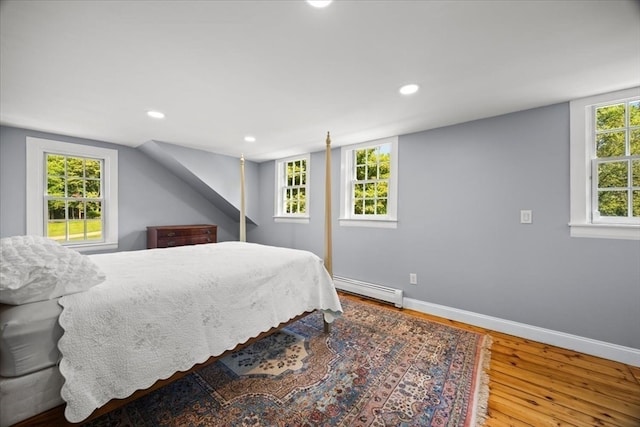 bedroom featuring multiple windows, hardwood / wood-style flooring, and baseboard heating