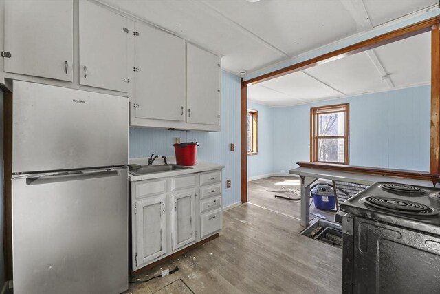 132 E Quincy St, North Adams, MA 01247 - kitchen with black / electric stove, a sink, baseboards, freestanding refrigerator, and white cabinetry