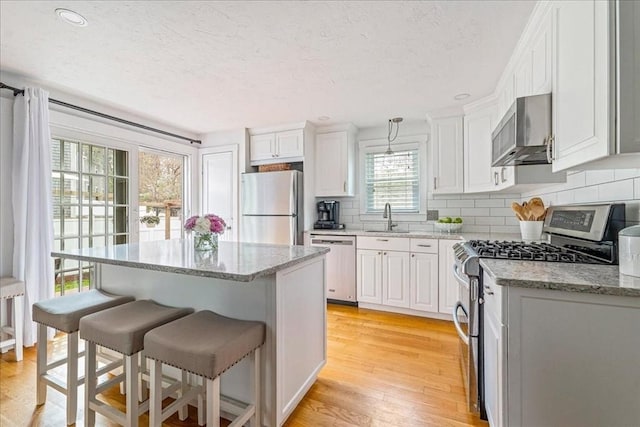 59 Brigantine Cir, Plymouth, MA 02360 - kitchen with stainless steel appliances, white cabinetry, a sink, a kitchen breakfast bar, and backsplash
