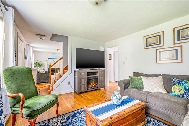59 Brigantine Cir, Plymouth, MA 02360 - living room featuring light wood finished floors, a warm lit fireplace, and stairway