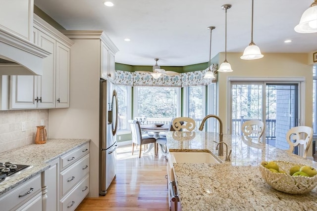 kitchen featuring tasteful backsplash, decorative light fixtures, light stone countertops, and white cabinets