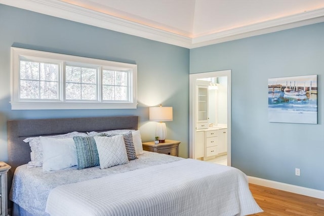 bedroom featuring crown molding, light hardwood / wood-style floors, and ensuite bath