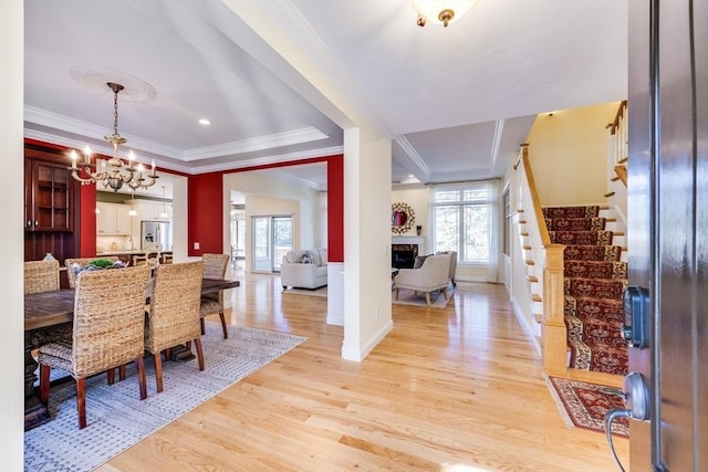 dining area with a wealth of natural light, ornamental molding, a chandelier, and light wood-type flooring