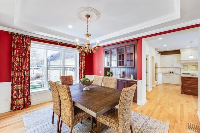 dining room featuring a tray ceiling, light hardwood / wood-style flooring, and ornamental molding