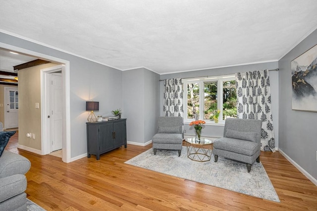 sitting room with wood finished floors, baseboards, and ornamental molding