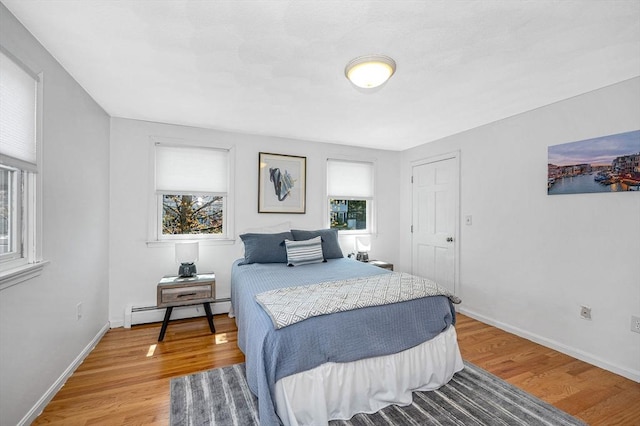 bedroom with light wood-style flooring, baseboards, baseboard heating, and multiple windows