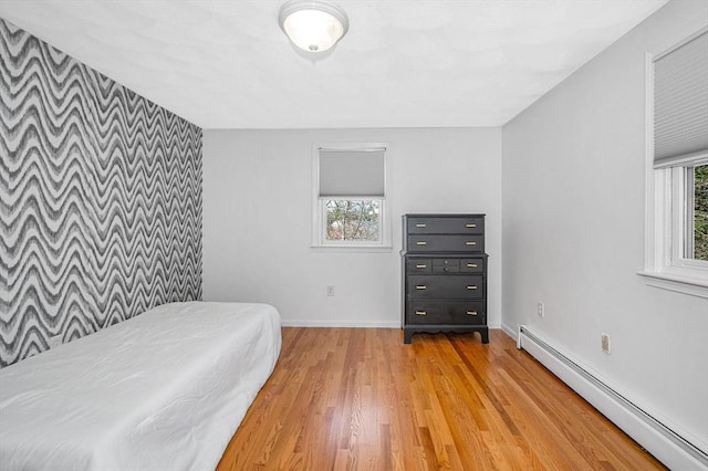 bedroom featuring a baseboard radiator, baseboards, and light wood finished floors