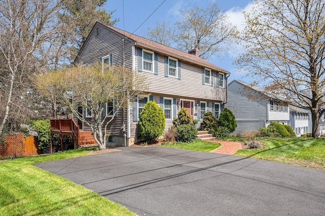 colonial inspired home featuring a front lawn and a chimney