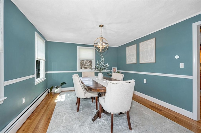 dining room featuring ornamental molding, baseboard heating, an inviting chandelier, and wood finished floors