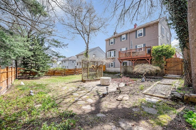 back of property featuring a chimney, a gate, a deck, and a fenced backyard