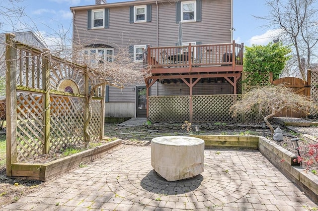 rear view of property featuring a gate, a deck, a patio, and fence