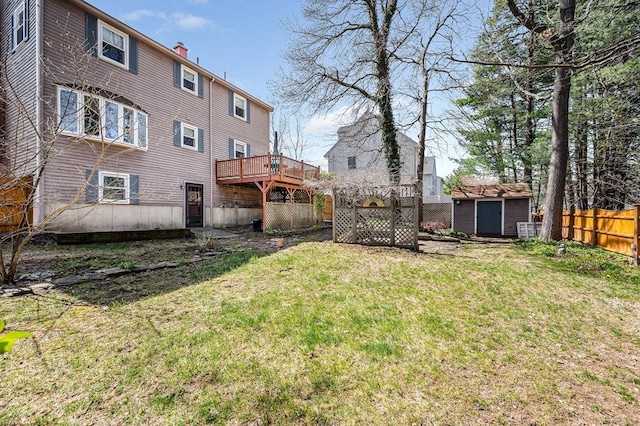 view of yard featuring an outdoor structure, a shed, a deck, and fence