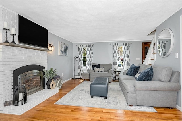 living area featuring a fireplace, crown molding, baseboards, and wood finished floors