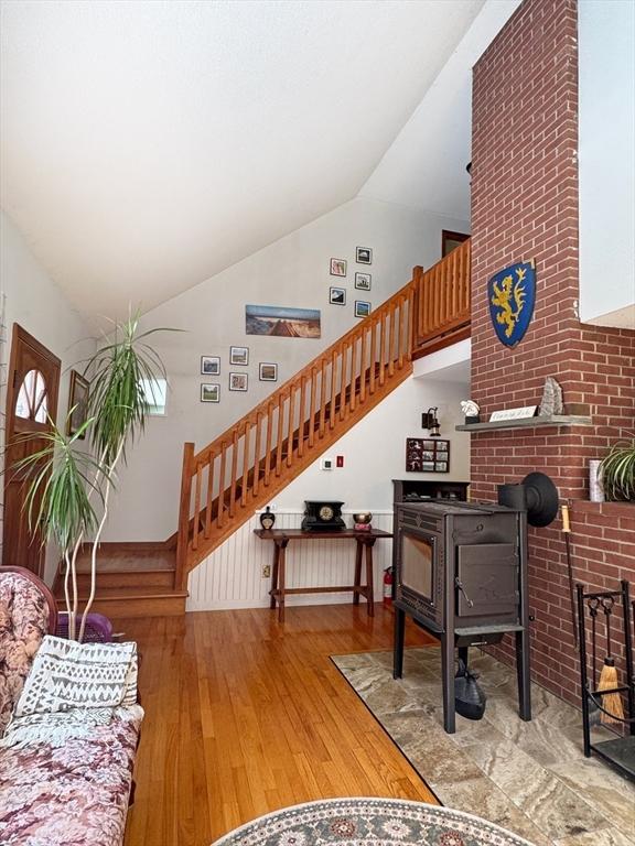 233 Old Wendell Rd, Northfield, MA 01360 - living area with hardwood / wood-style flooring, stairway, a wood stove, and high vaulted ceiling