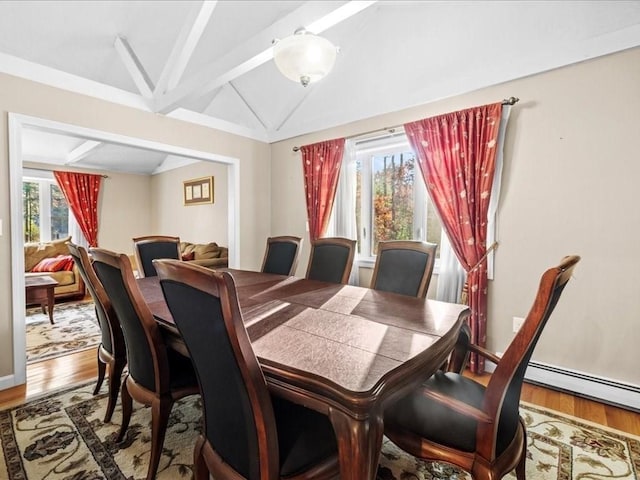 dining room with a baseboard heating unit, lofted ceiling with beams, and wood finished floors