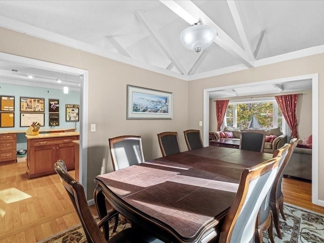 dining area featuring light wood-type flooring and lofted ceiling with beams