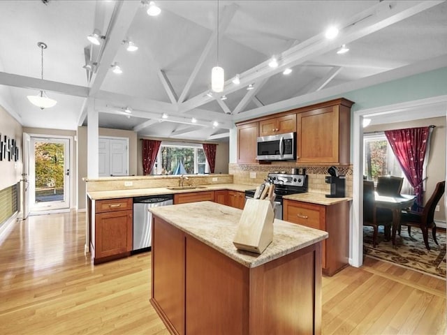 kitchen with vaulted ceiling with beams, light wood-style flooring, a peninsula, stainless steel appliances, and a sink