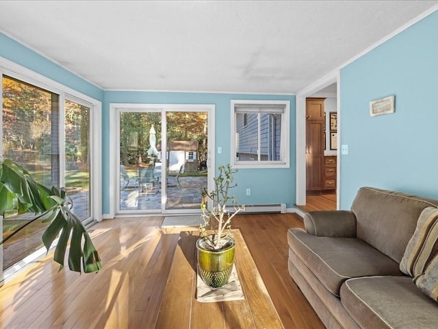 living room featuring ornamental molding, baseboards, wood-type flooring, and a baseboard radiator