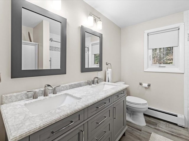 full bathroom featuring a sink, toilet, wood finished floors, and a baseboard radiator