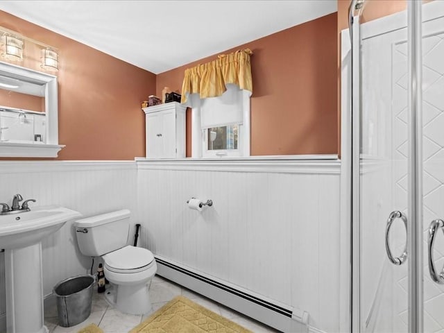 bathroom featuring tile patterned floors, toilet, a sink, wainscoting, and a baseboard radiator