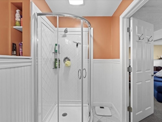 bathroom with connected bathroom, a shower stall, and wainscoting