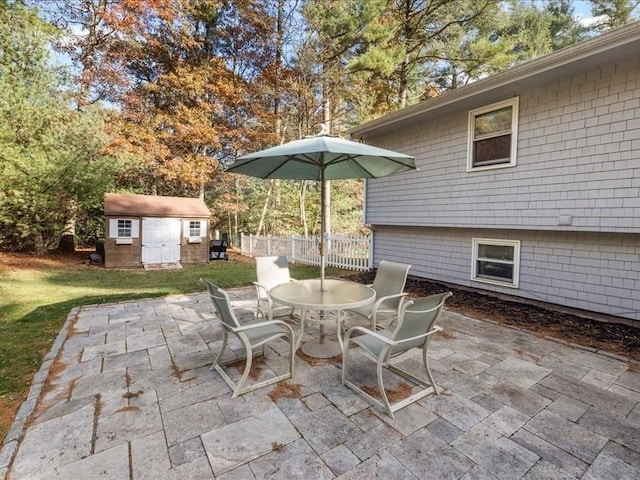 view of patio with an outbuilding, outdoor dining area, fence, and a shed