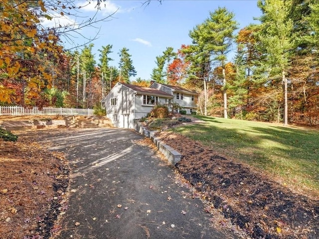 view of front of property with aphalt driveway, a front lawn, and fence