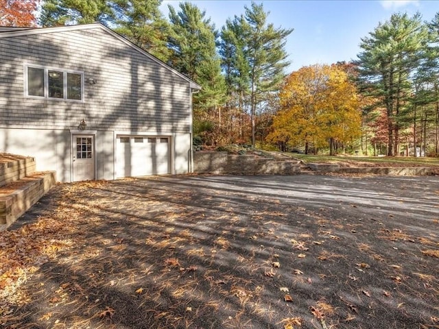 view of side of home with aphalt driveway and an attached garage