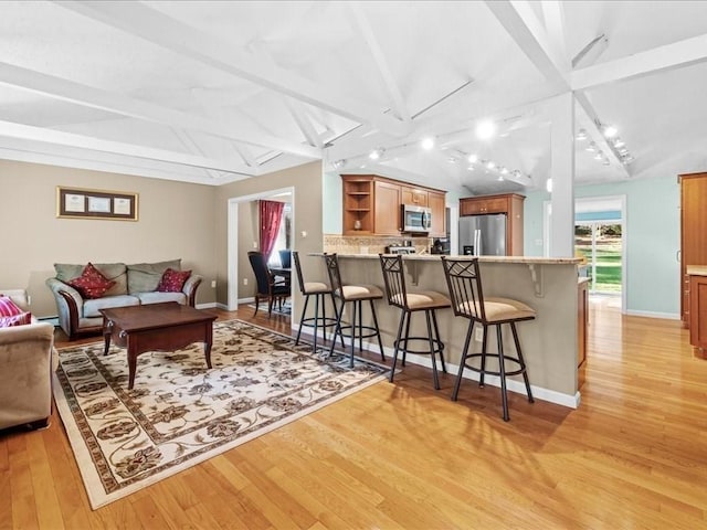 living room featuring vaulted ceiling with beams, light wood-type flooring, and baseboards